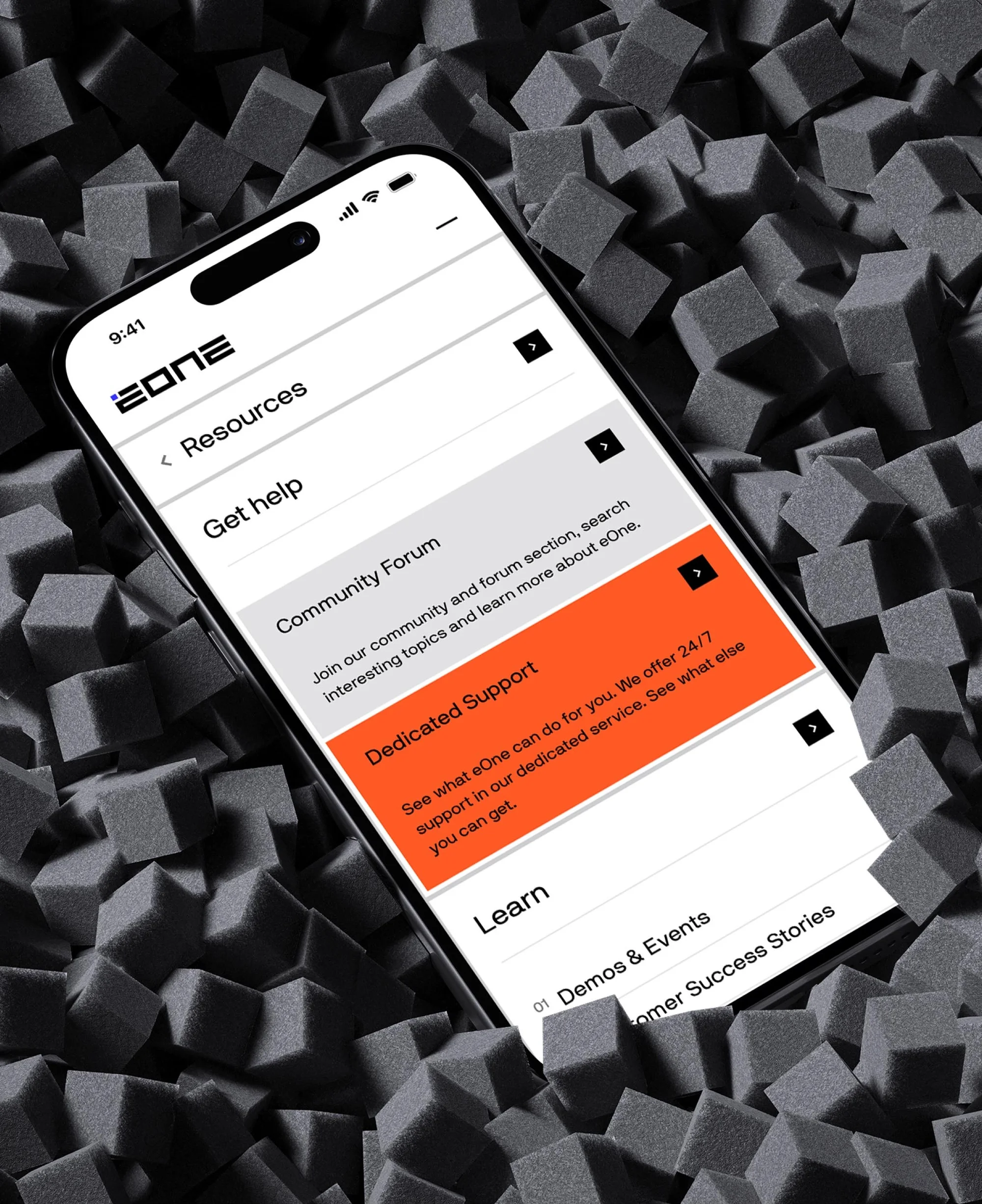 Smartphone displaying a mobile app interface with 'Resources' and 'Get Help' options, surrounded by a geometric foam material.