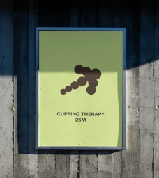 Framed sign with light green background and dark brown circular arrow graphic mounted on dark vertical wooden plank wall