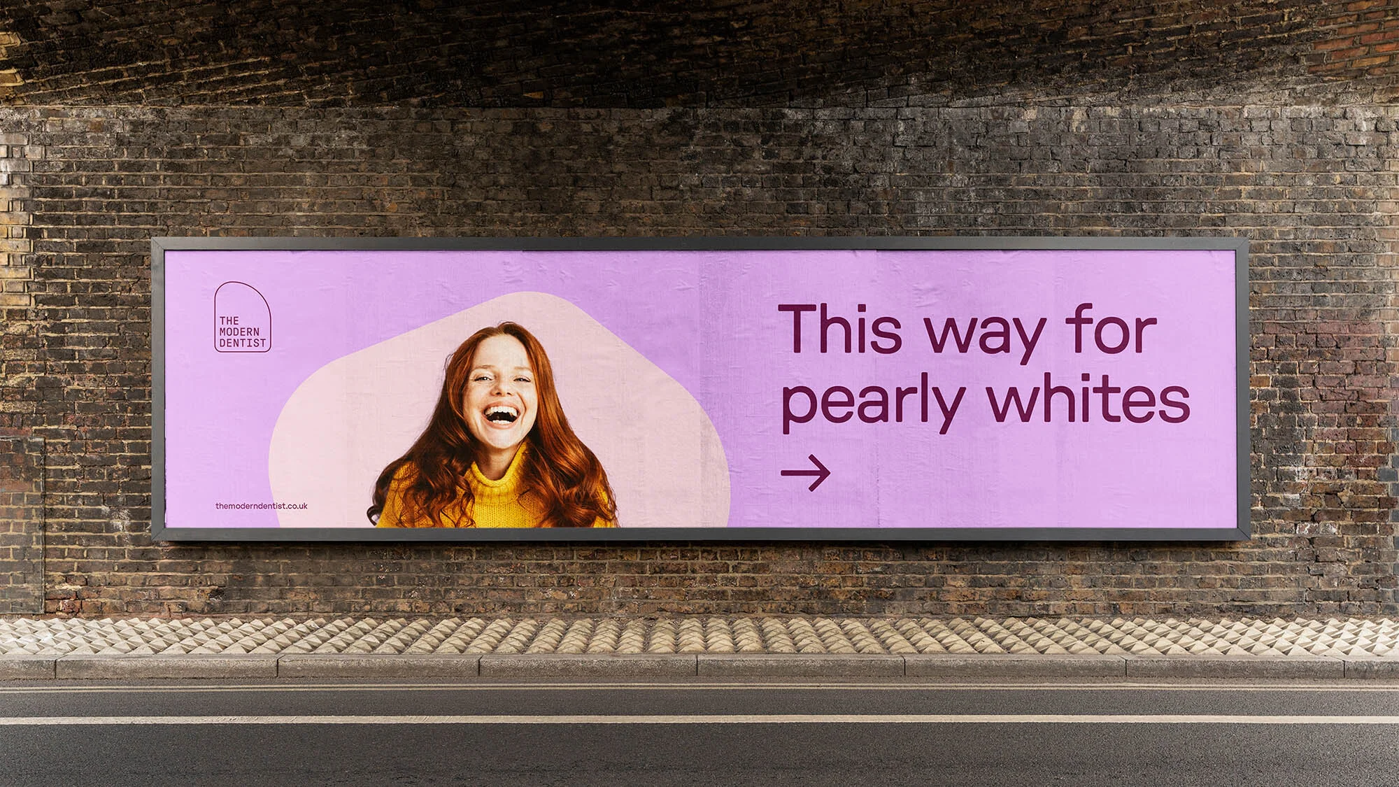 Outdoor billboard featuring a smiling red-haired woman and an advertisement for a dental practice with the text 'This way for pearly whites'.