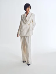 Model wearing a white pinstripe suit against a bright white seamless background for BOSS