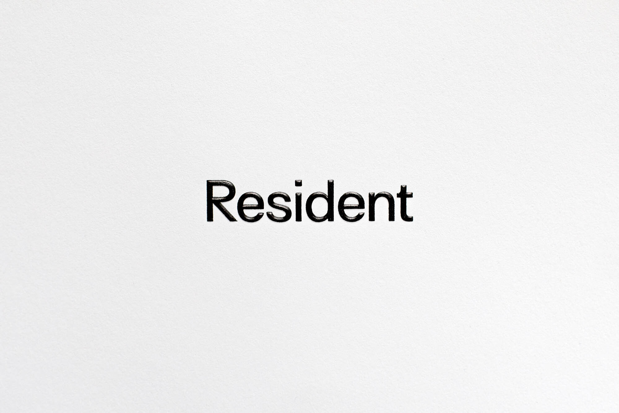The word 'Resident' in black sans-serif font is centered against a stark white background, creating a minimalist and high-contrast image.