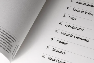 Close-up of a printed brand identity guidelines document with a visible table of contents on textured white paper.