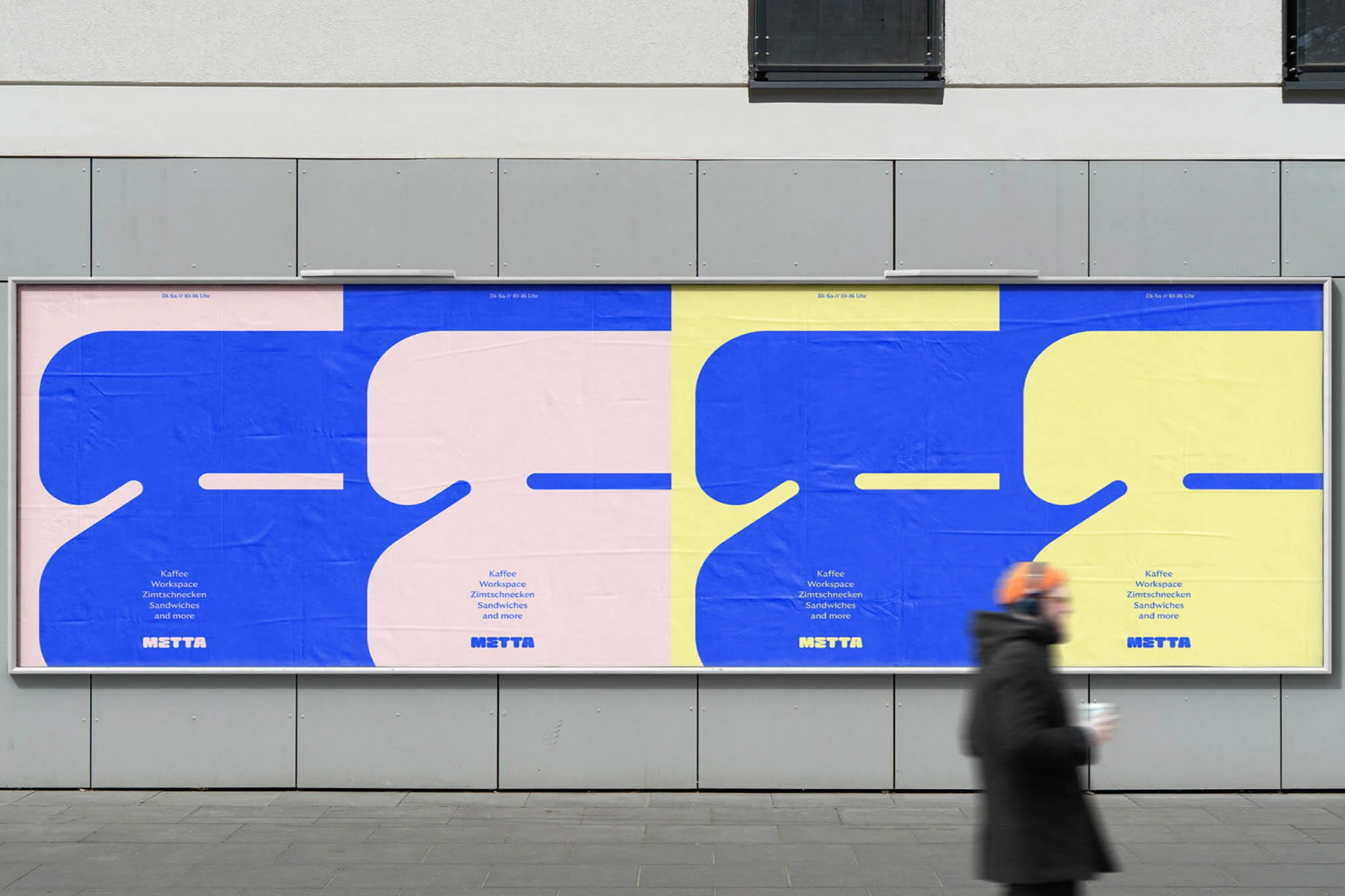 Metta brand identity billboard with blue and yellow graphic posters mounted on a grey concrete wall