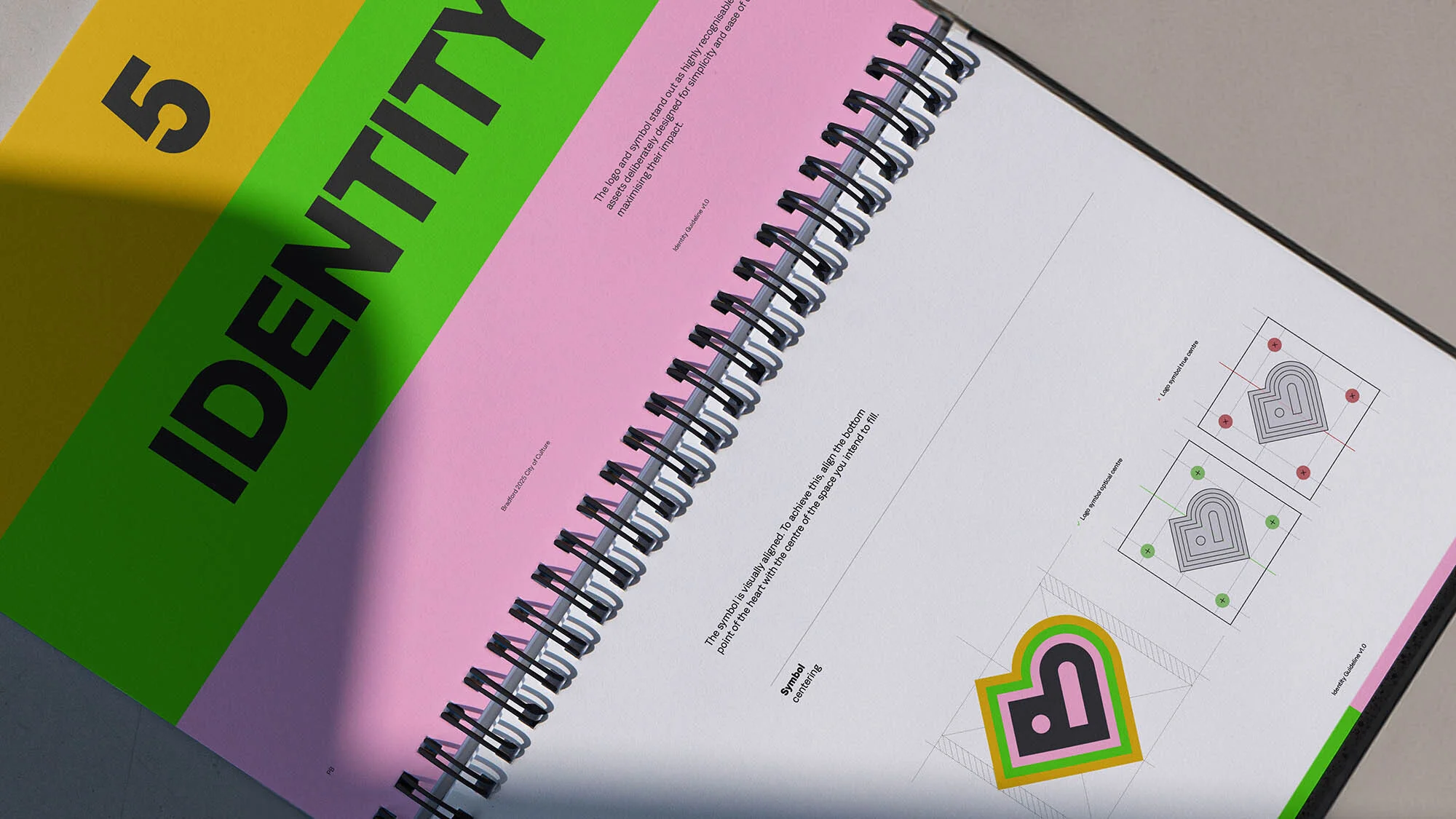Open spiral notebook page featuring logo design and the word 'Identity' in bold. Graphic design concept in a studio setting.