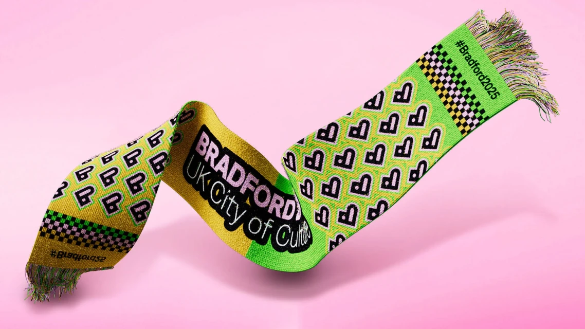 Brightly colored Bradford City of Culture 2025 scarf featuring a pattern of B letters on a pink backdrop with soft lighting.