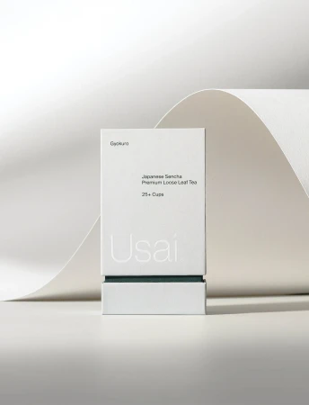 Product shot of a white tea box with minimalist design featuring the brand name Usai, set against a soft, neutral background.