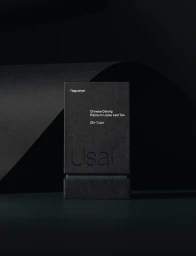 Black textured packaging box for Usai loose leaf tea set against a dark studio background