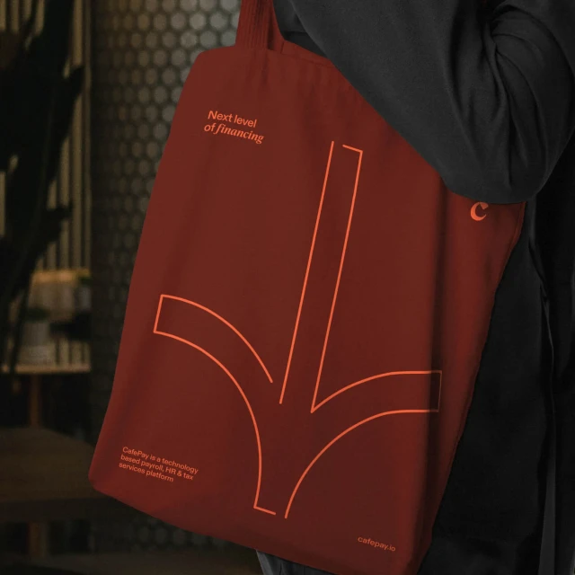A person is holding a dark red tote bag with a light red arrow design pointing downwards, alongside text about financial technology.