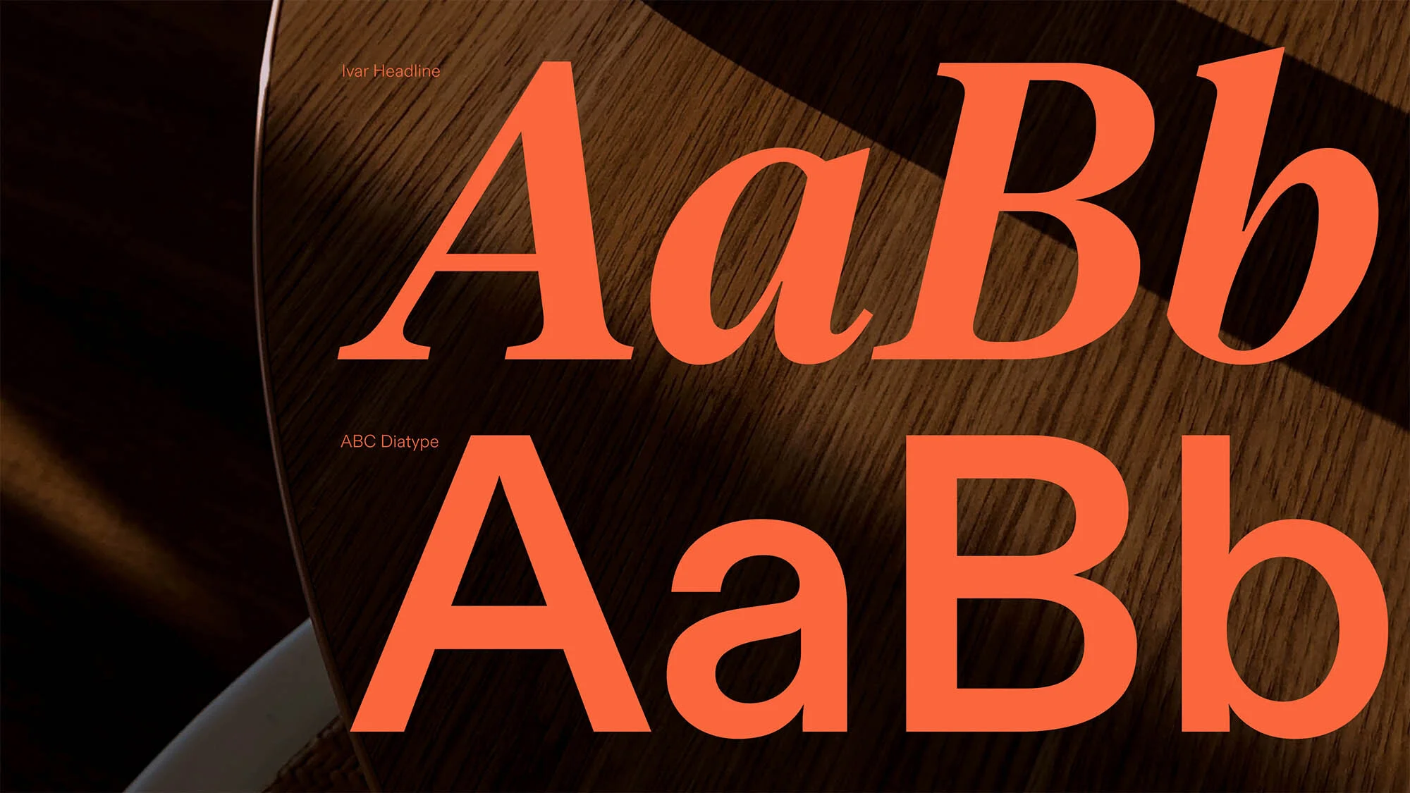 Close-up of two font typefaces, 'Ivar Headline' and 'ABC Diatype,' in orange lettering, over a dark brown wood-grain surface.