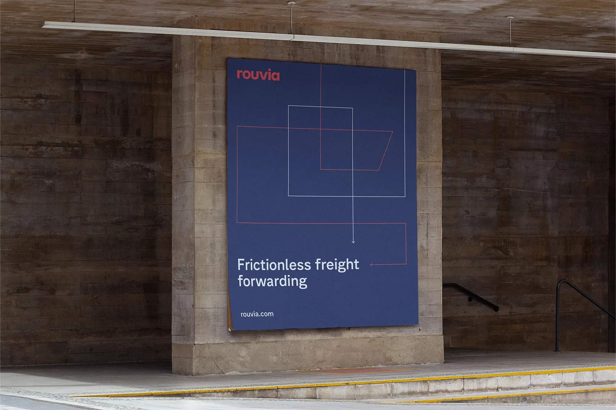 Large blue ROUVIA advertisement on a concrete wall with geometric line art and the text, 'Frictionless freight forwarding'.