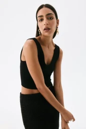 Model wearing a black scoop neck top and dark skirt against a bright white background for H&M summer 2025.