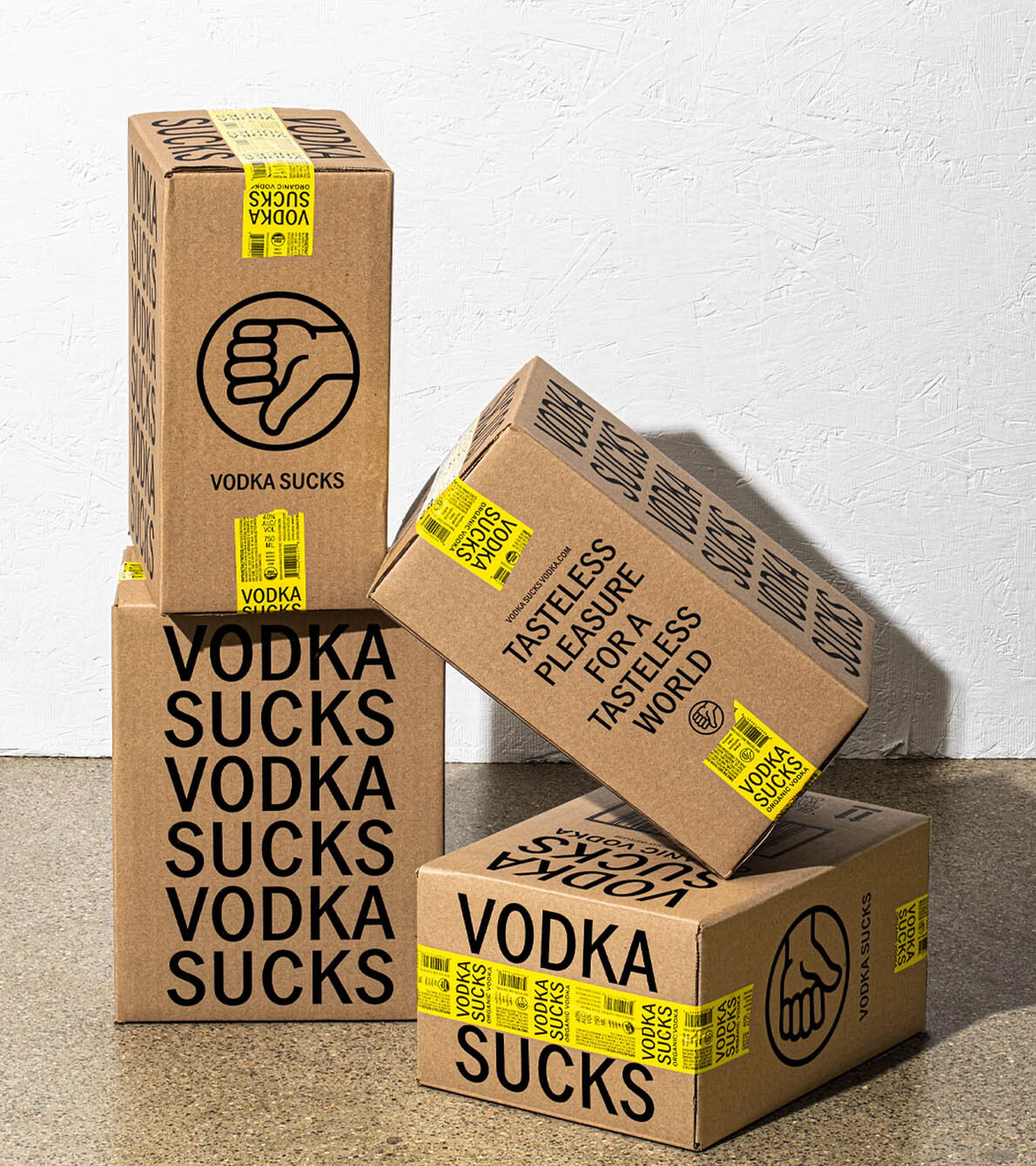 Four cardboard boxes stacked with 'Vodka Sucks' branding on a light surface. Stacked boxes angled on neutral surface.