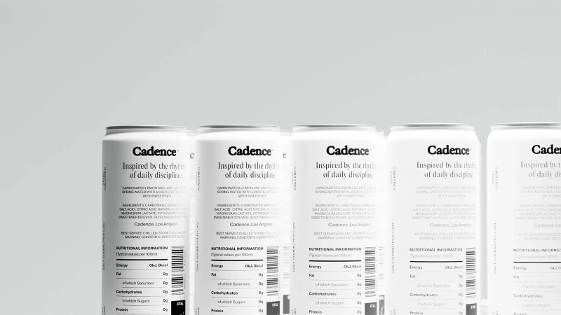 Multiple white cans of Cadence brand carbonated lemon and lime flavored spring water are lined up against a white background in a studio shot.