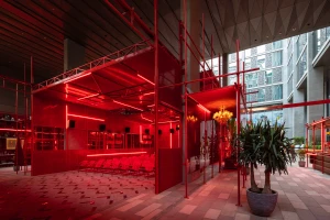 Interior shot of Cinema Akil brand identity installation featuring red scaffolding structure, neon lighting, and red cinema seating.