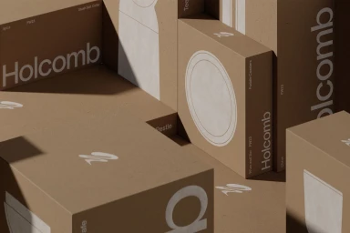 Stacked brown cardboard packaging boxes featuring white Holcomb brand typography and product illustrations