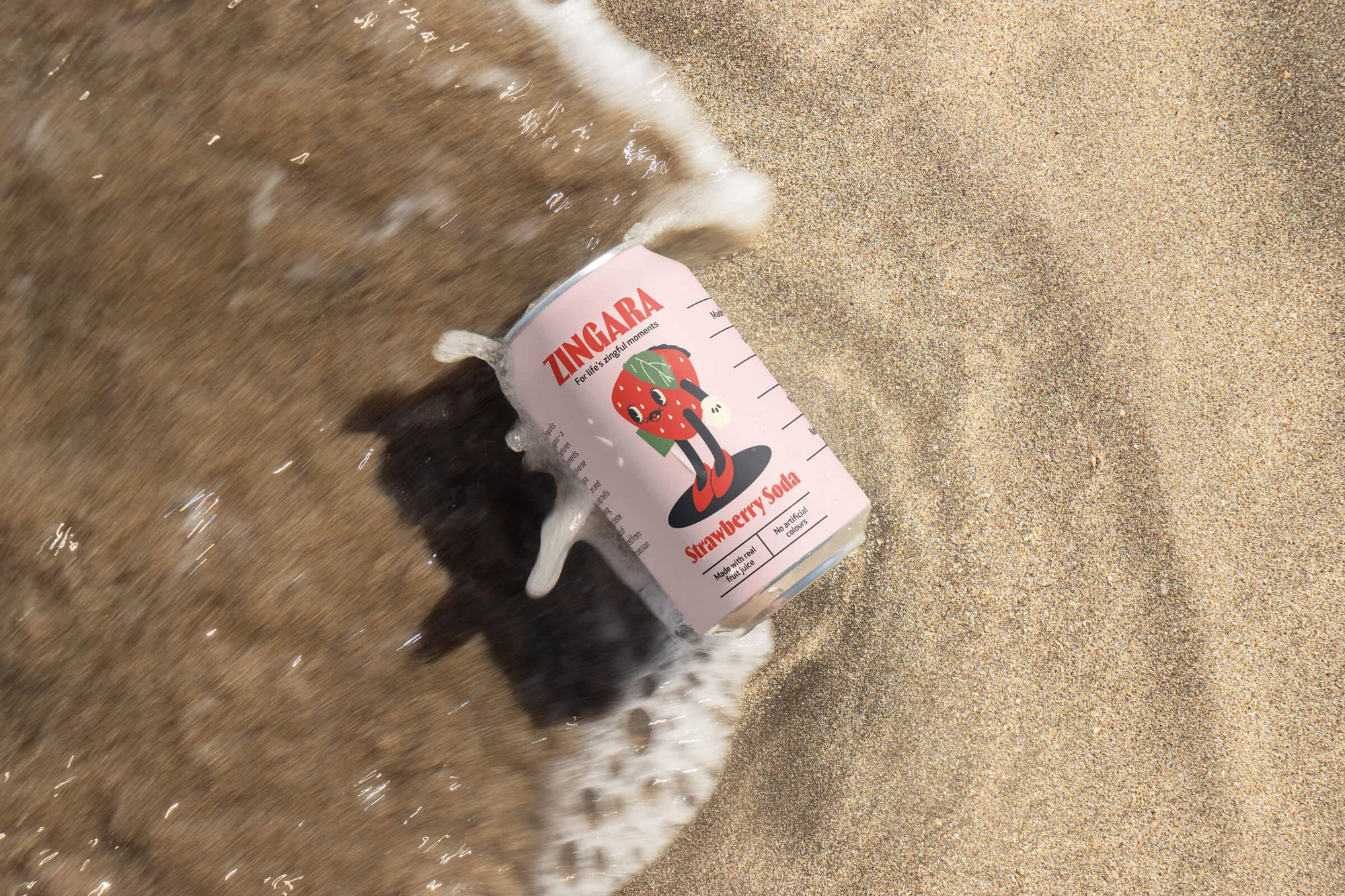 Strawberry soda can in wet sand by surf. Pink Zingara can with strawberry mascot in waves on beach. Food and beverage photography.