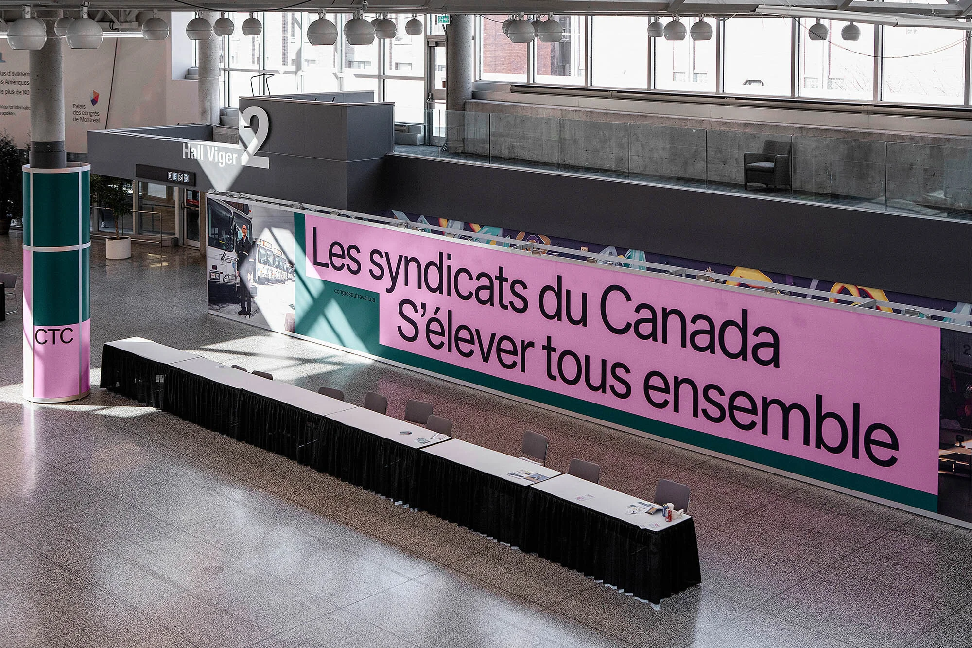 Large indoor space featuring a long table, banner with text 'Les syndicats du Canada S'élever tous ensemble', and modern architectural details.