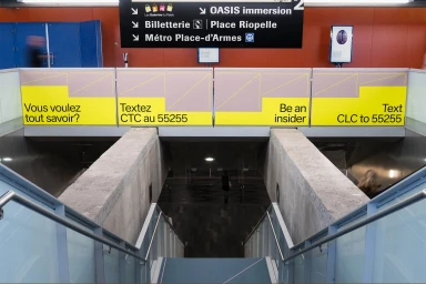 Public transit station interior with bilingual signage, stairways, and graphic panels created by Baillat Studio for the Canadian Labour Congress.