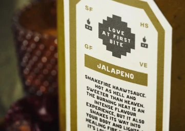 Close up product packaging label for Snakefire brand featuring typographic text and gold and white design details.
