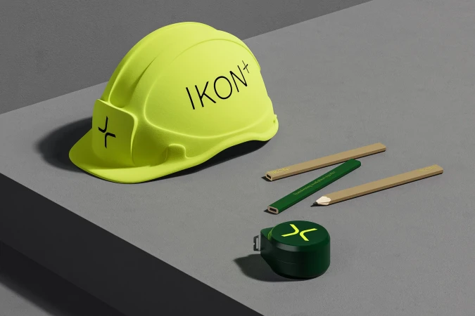 Still life of a construction helmet, pencils, and tape measure on a grey surface, suitable for construction or engineering concepts.