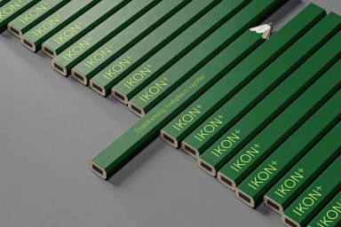 An overhead diagonal composition featuring parallel green branded pencils with yellow lettering resting on a grey surface.