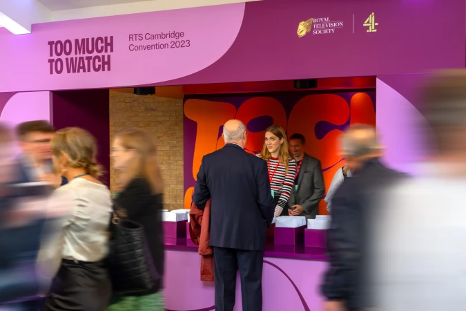 People gathering at the RTS Cambridge Convention 2023 check-in, featuring convention signage and event branding.