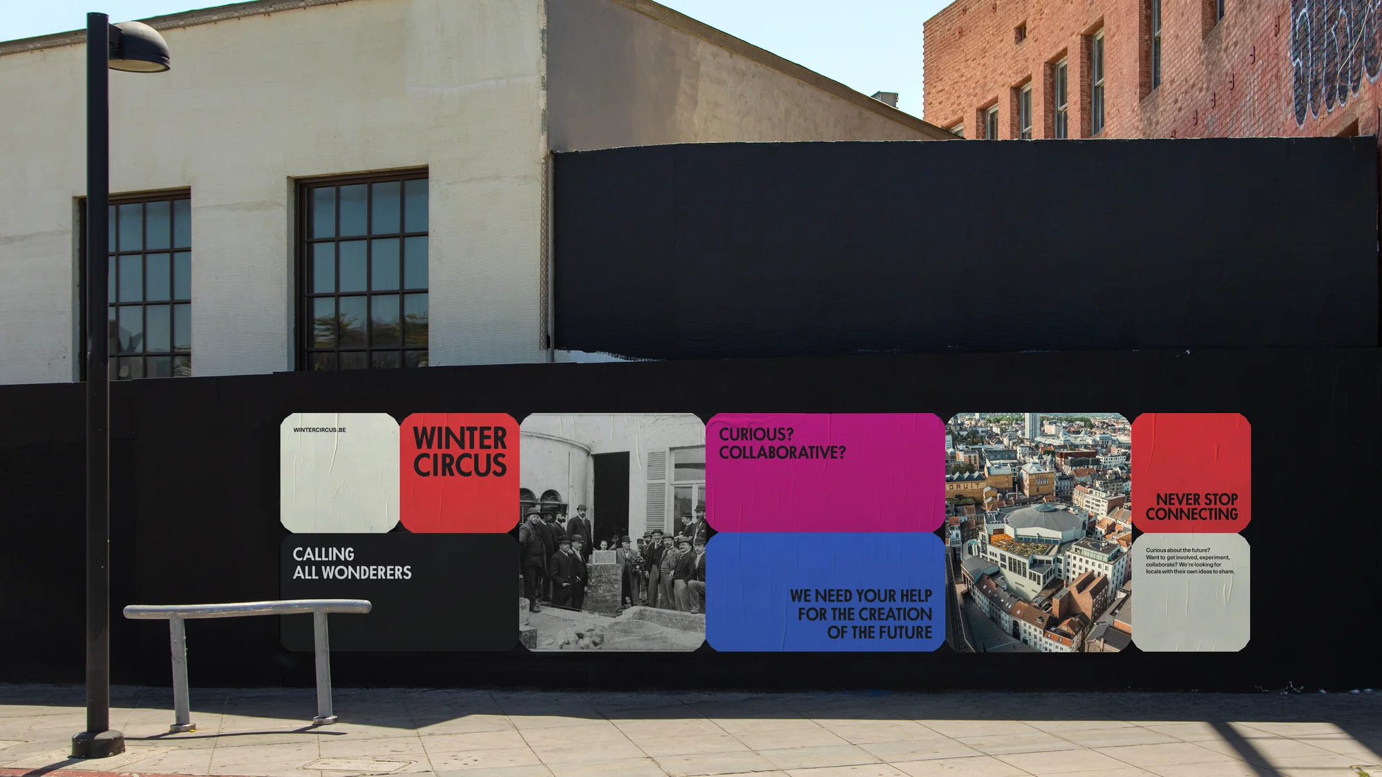 A modern public art installation on a city street displays colorful graphic posters with architectural and urban design themes on a black wall.