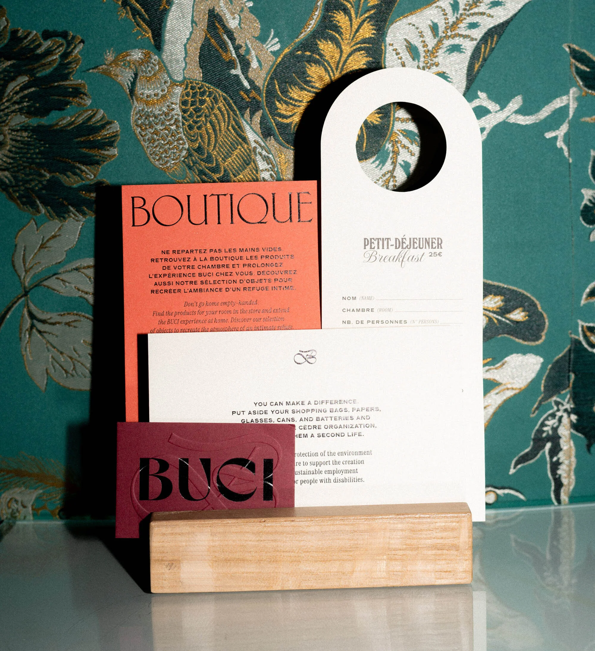 Stationery set featuring business cards and printed marketing materials against a textured botanical wallpaper backdrop, creating a scene.