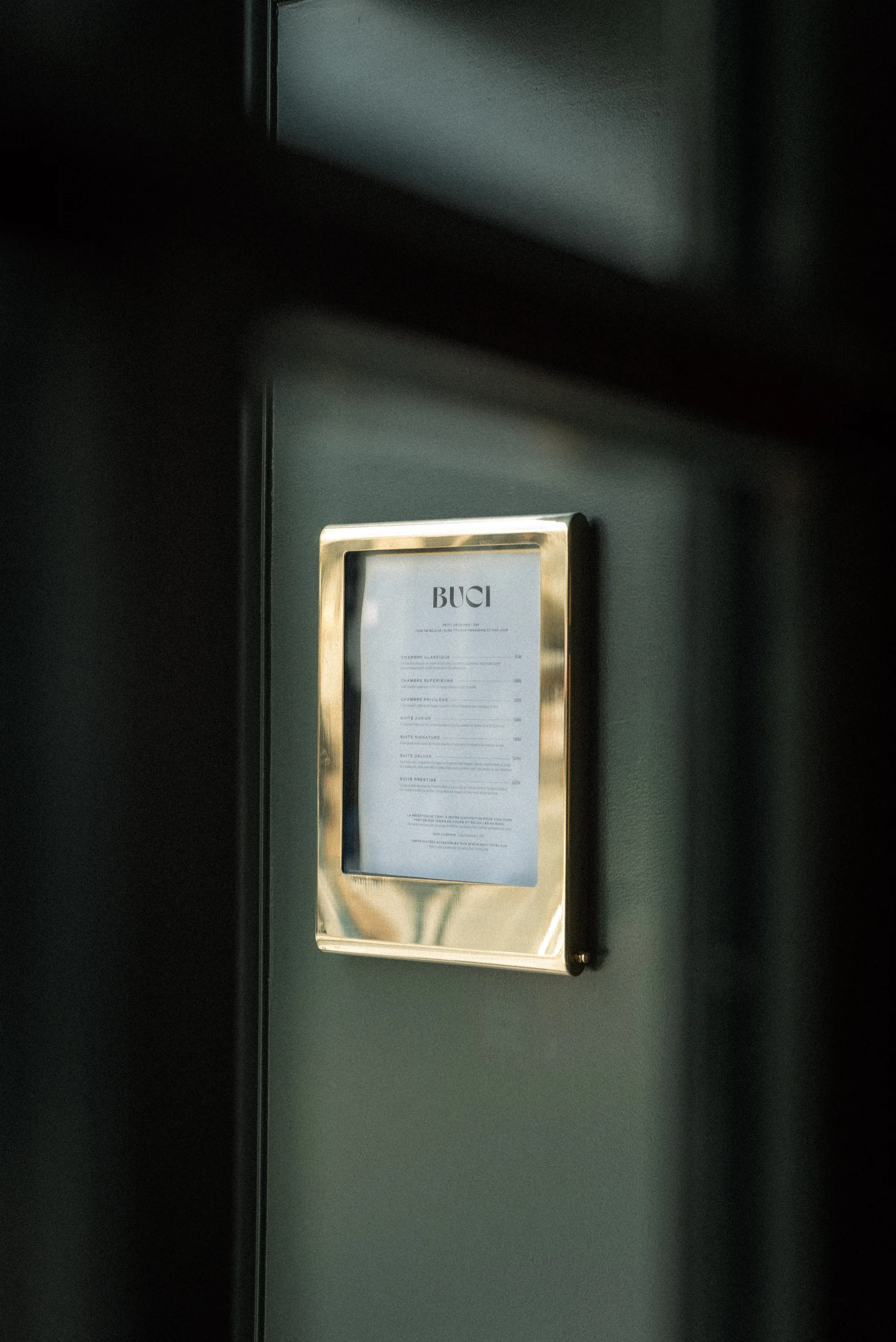 Restaurant menu in a golden frame on a dark grey wall, offering a glimpse of the establishment's offerings.