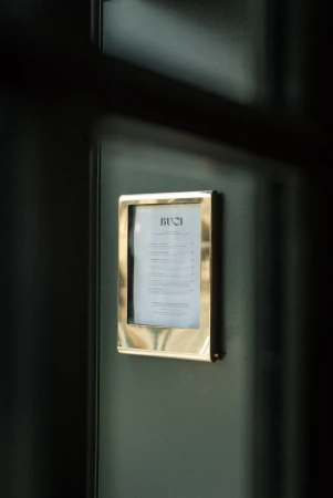 Restaurant menu in a golden frame on a dark grey wall, offering a glimpse of the establishment's offerings.