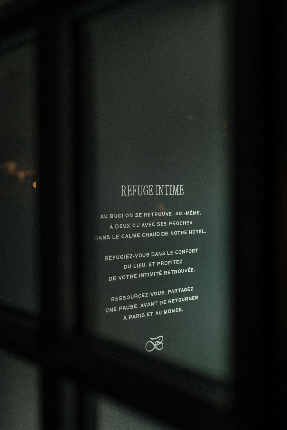 French typography displayed on a dark glass surface with brand identity elements for Hotel Buci