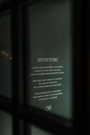 French typography displayed on a dark glass surface with brand identity elements for Hotel Buci
