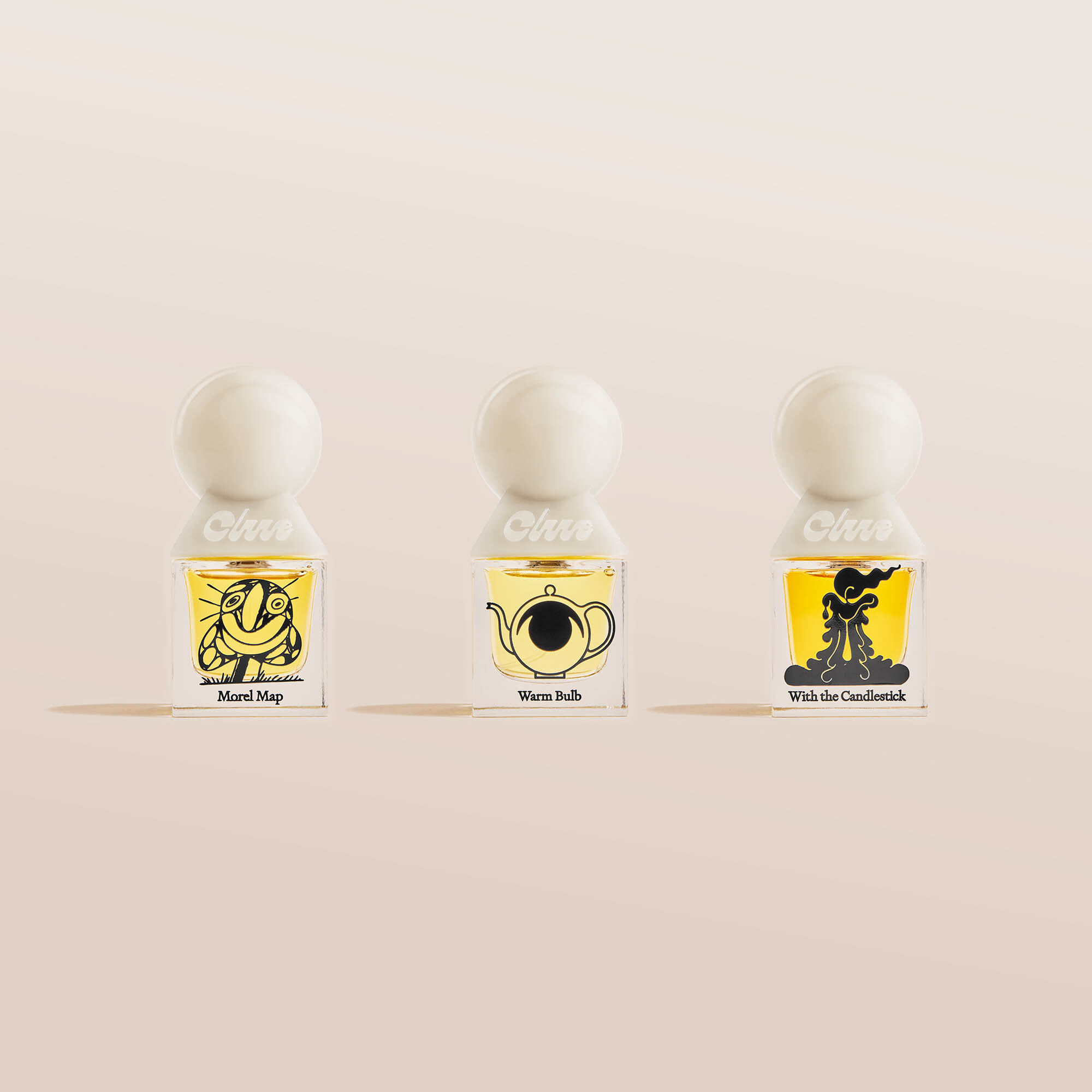 Three glass bottles of scented oil perfume sit in a row. Each has a different black-and-yellow cartoon drawing and a white round cap.