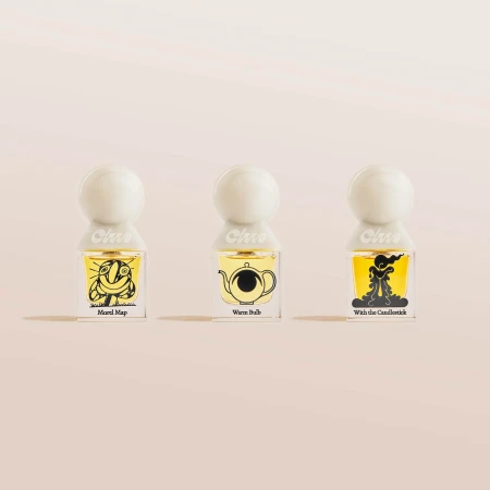 Three glass bottles of scented oil perfume sit in a row. Each has a different black-and-yellow cartoon drawing and a white round cap.