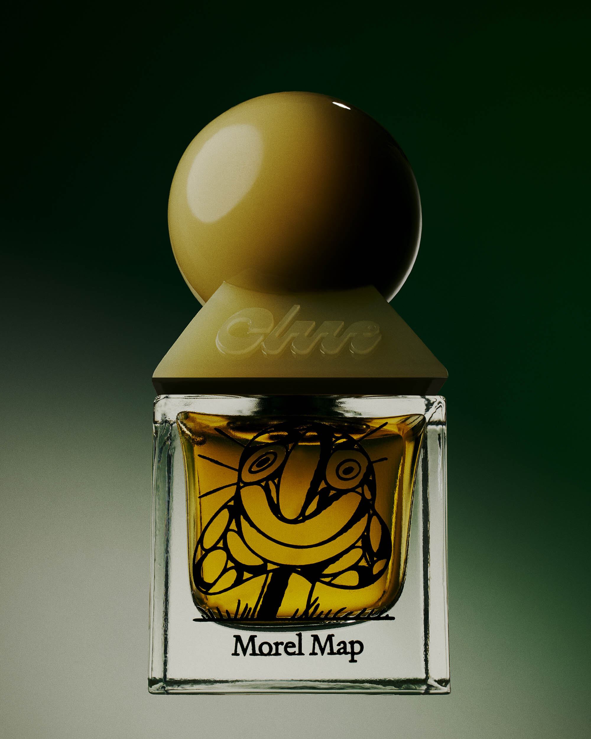 Close-up studio shot of a square glass perfume bottle with a tan sphere cap, featuring a sketched face design and the words "Morel Map."