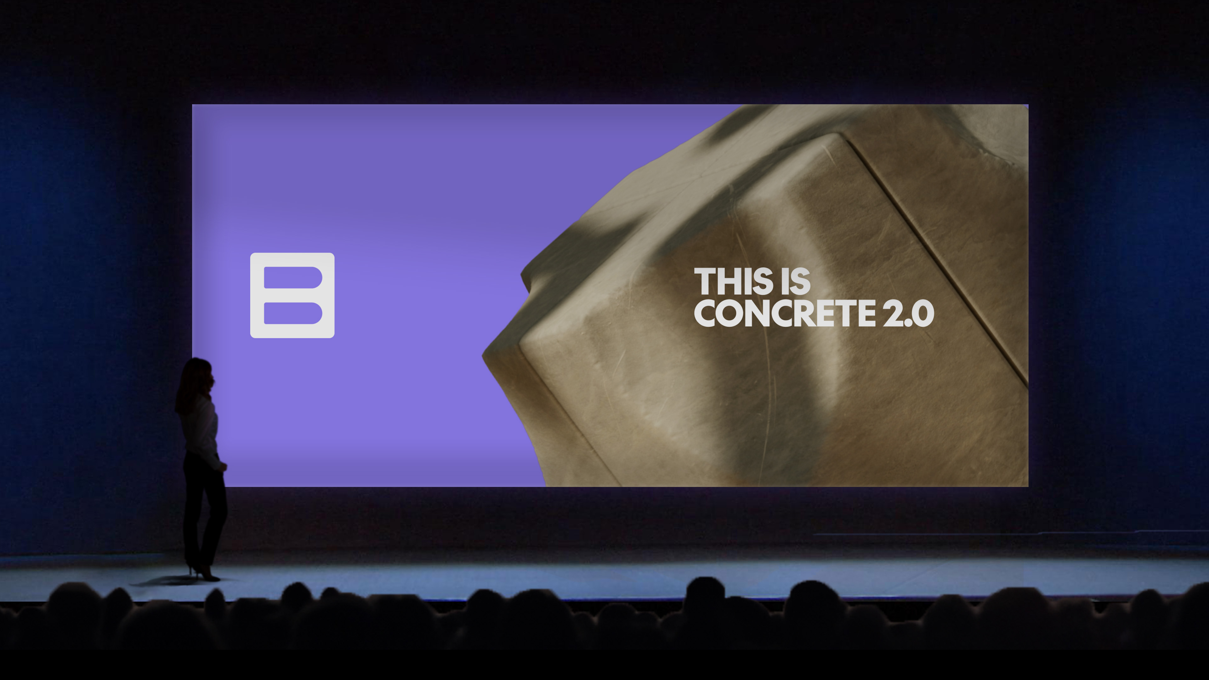 Presentation stage with a woman standing in front of a large screen displaying a logo and the text 'This is Concrete 2.0'.