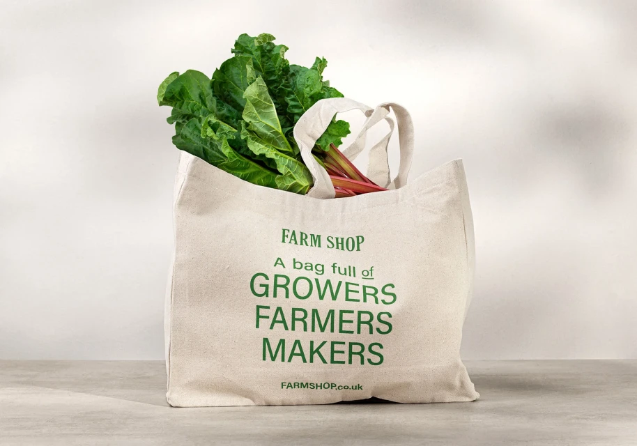 Farm shop tote bag filled with fresh green vegetables. Sustainable shopping promoting local growers, farmers, and makers.