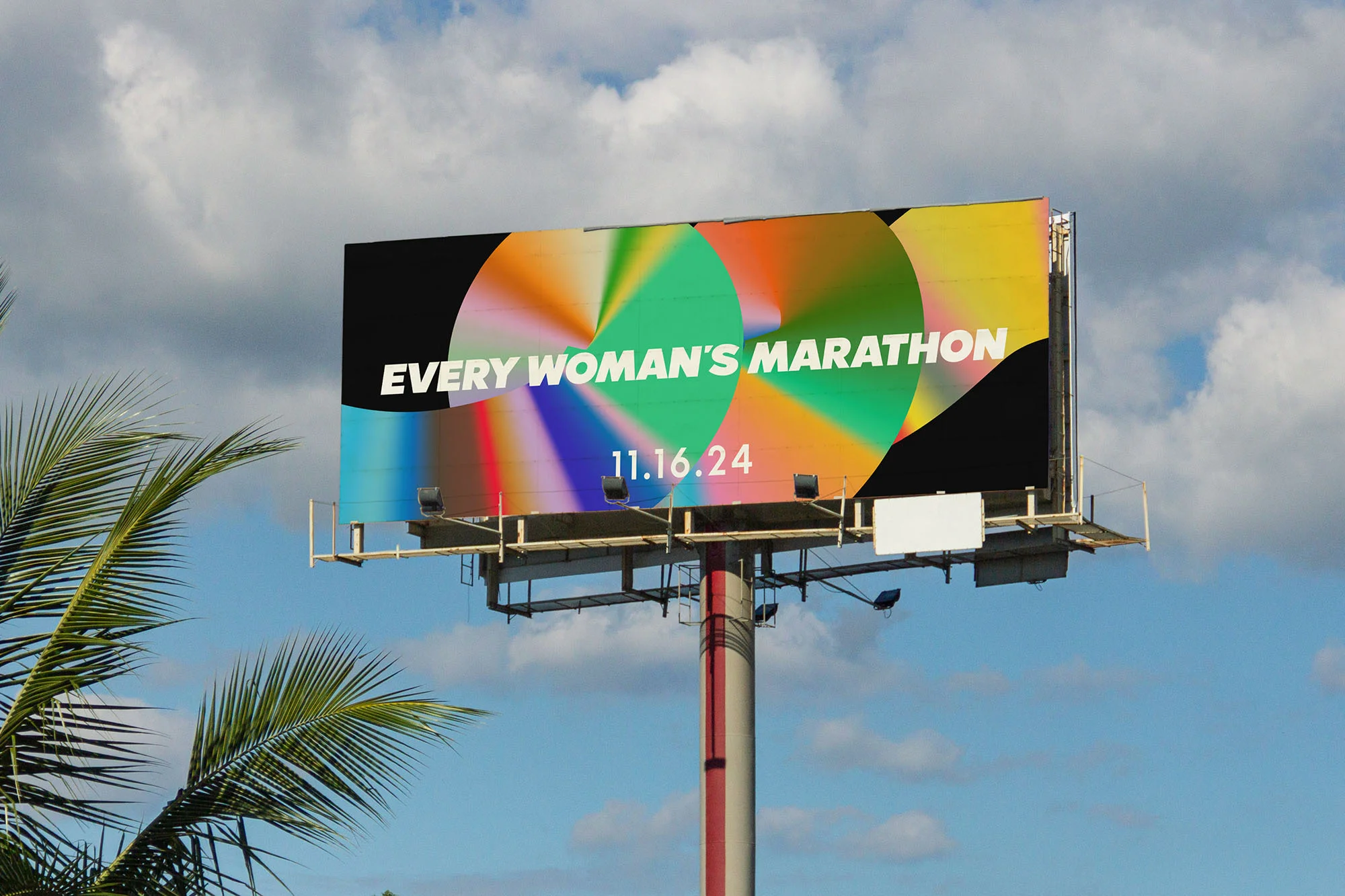 Billboard advertising the 'Every Woman's Marathon' set against a cloudy sky and palm fronds. The event date is November 16, 2024.