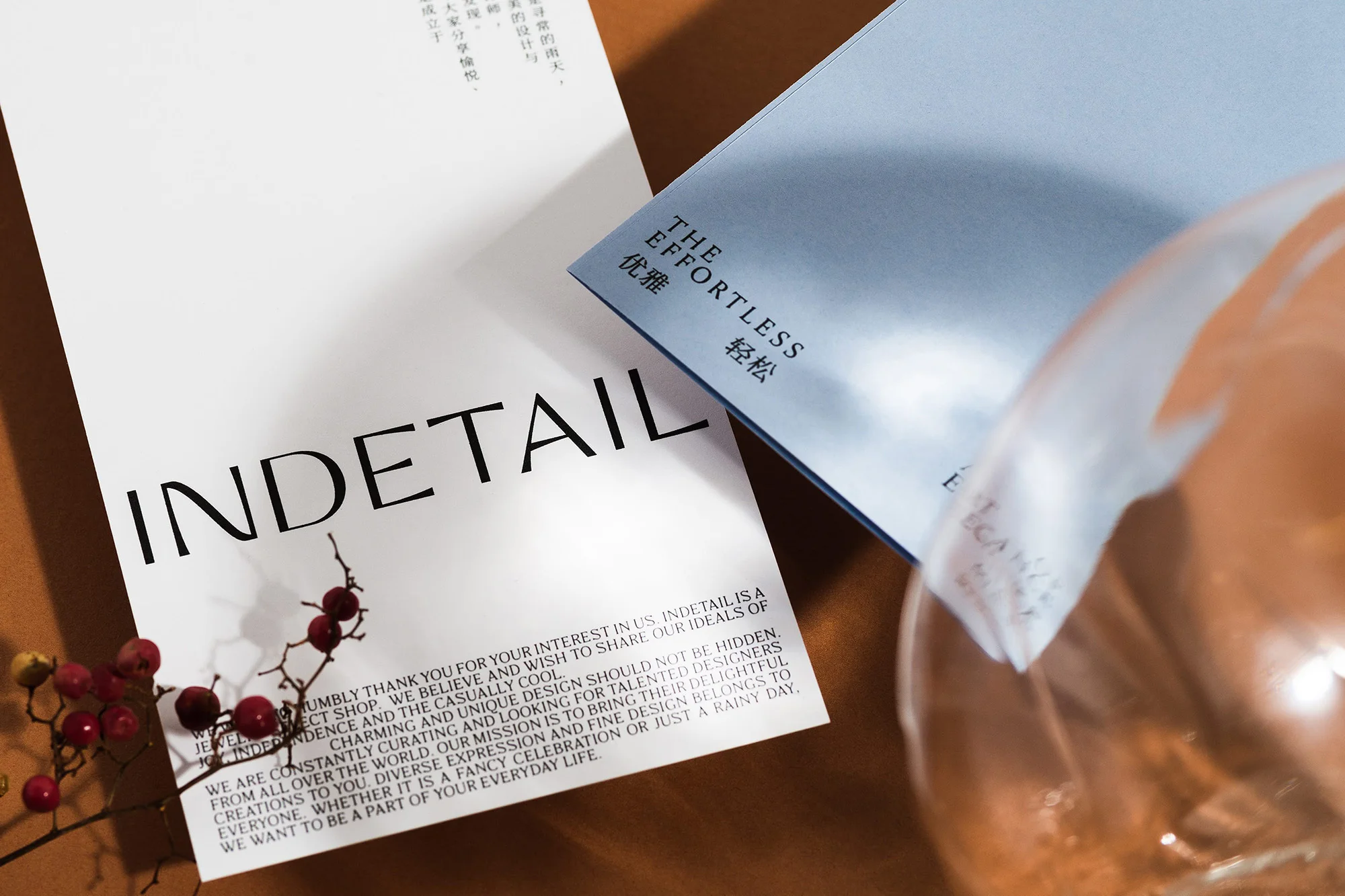 Overhead studio shot of two paper cards with minimalist typography, resting on a brown surface next to a small decorative branch.