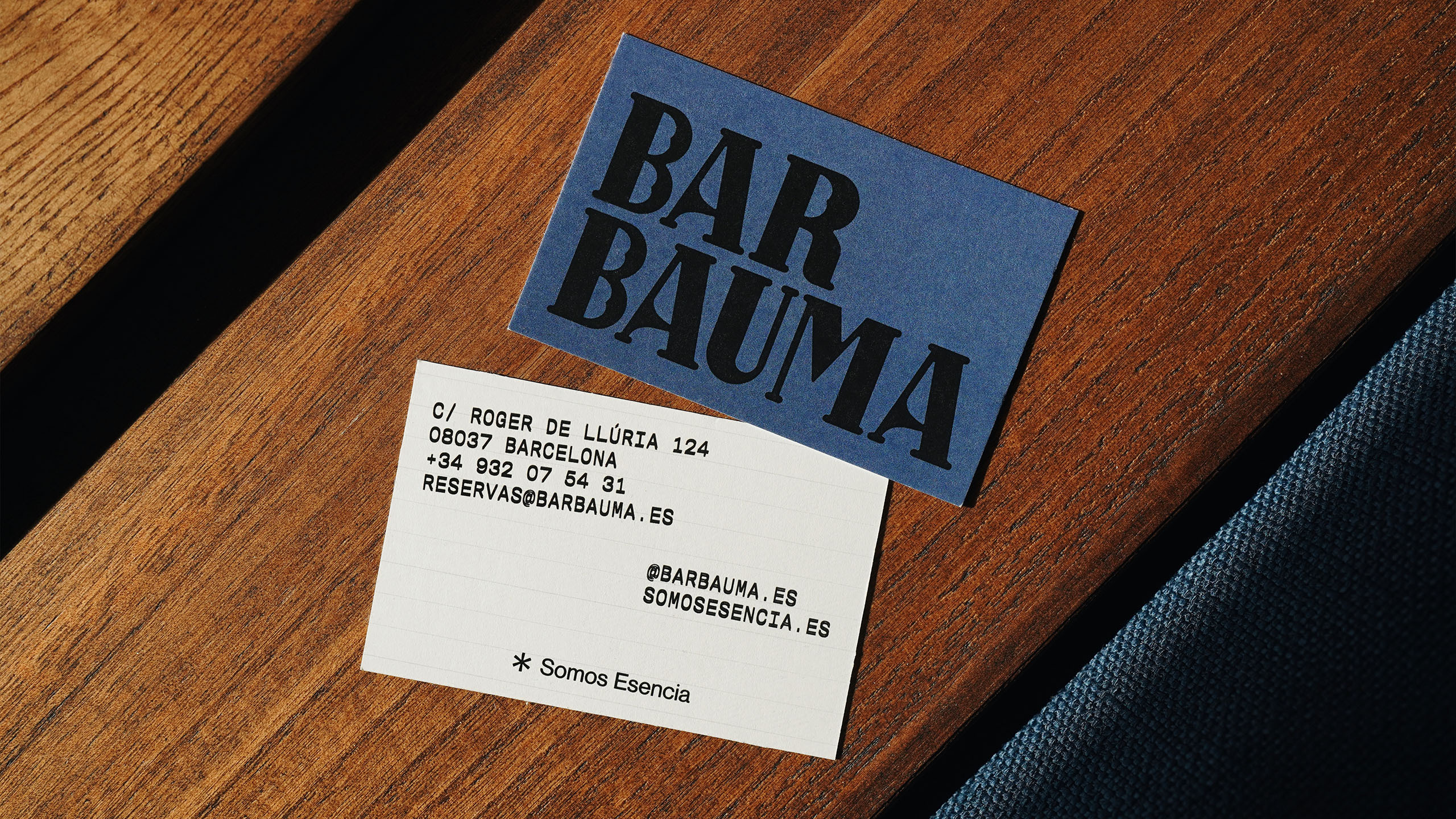 Close-up of business cards for Bar Bauma restaurant on wood surface, featuring modern typography and clean design, with a blue accent card.