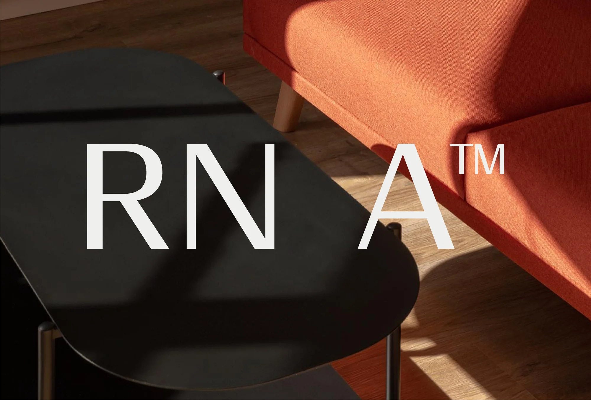 Interior shot of a black coffee table with white text overlay in front of an orange sofa on a wood floor with sunlight.