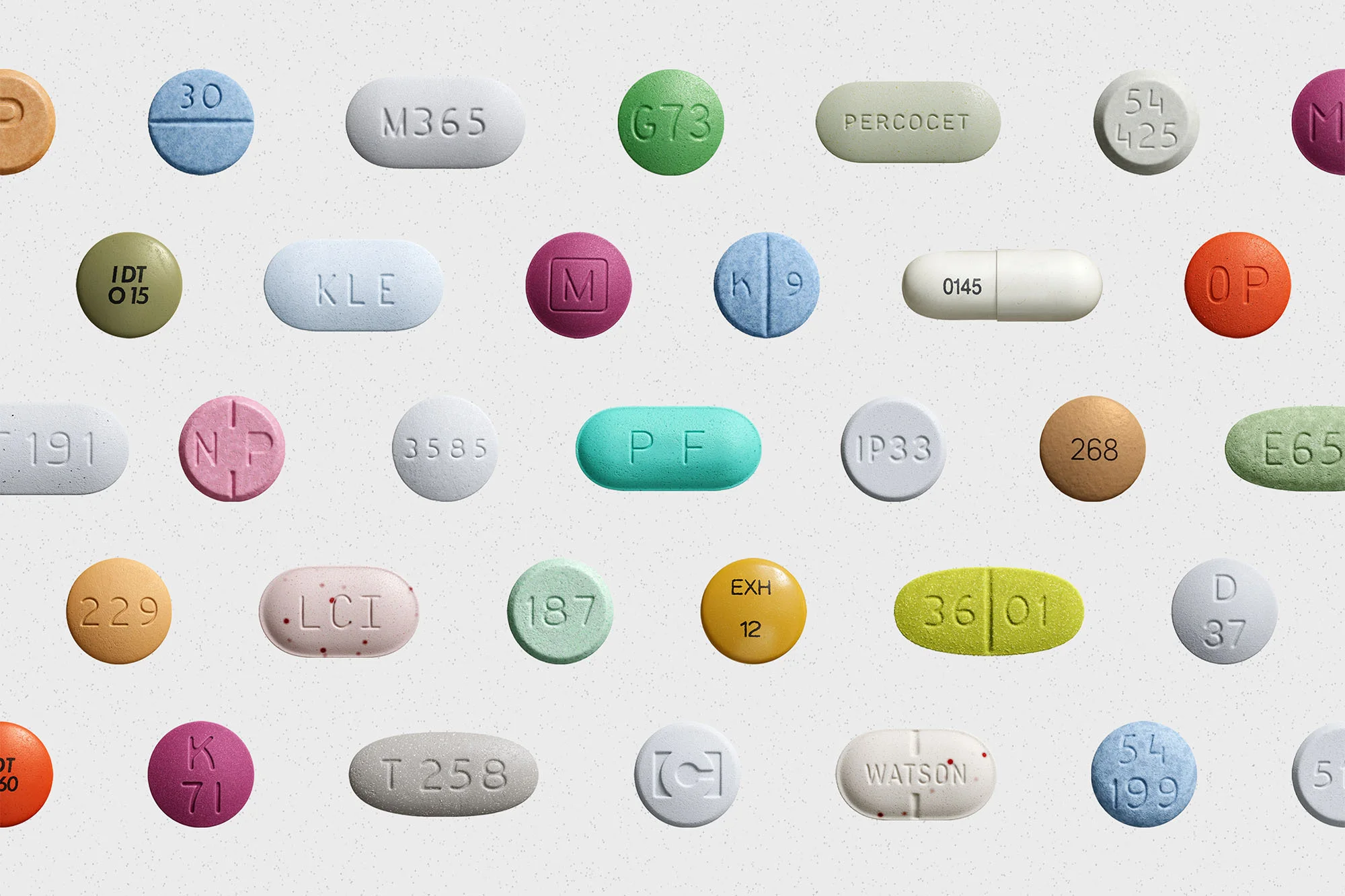 Macro photograph of assorted pills and tablets in various colors, shapes, and sizes, arranged on a seamless white background.