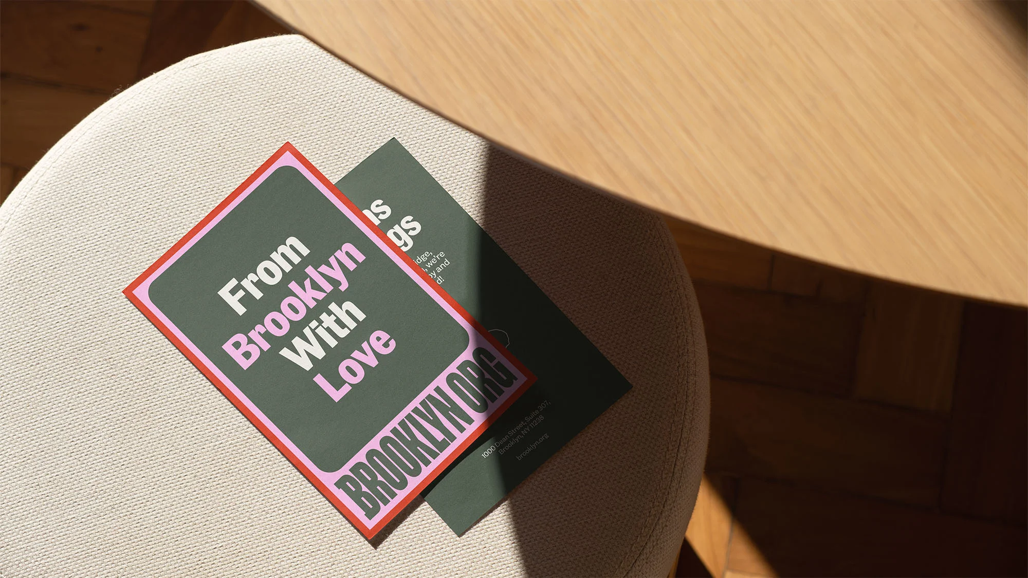 Close-up of postcards on a beige chair, featuring the text "From Brooklyn With Love" and the website brooklyn.org.
