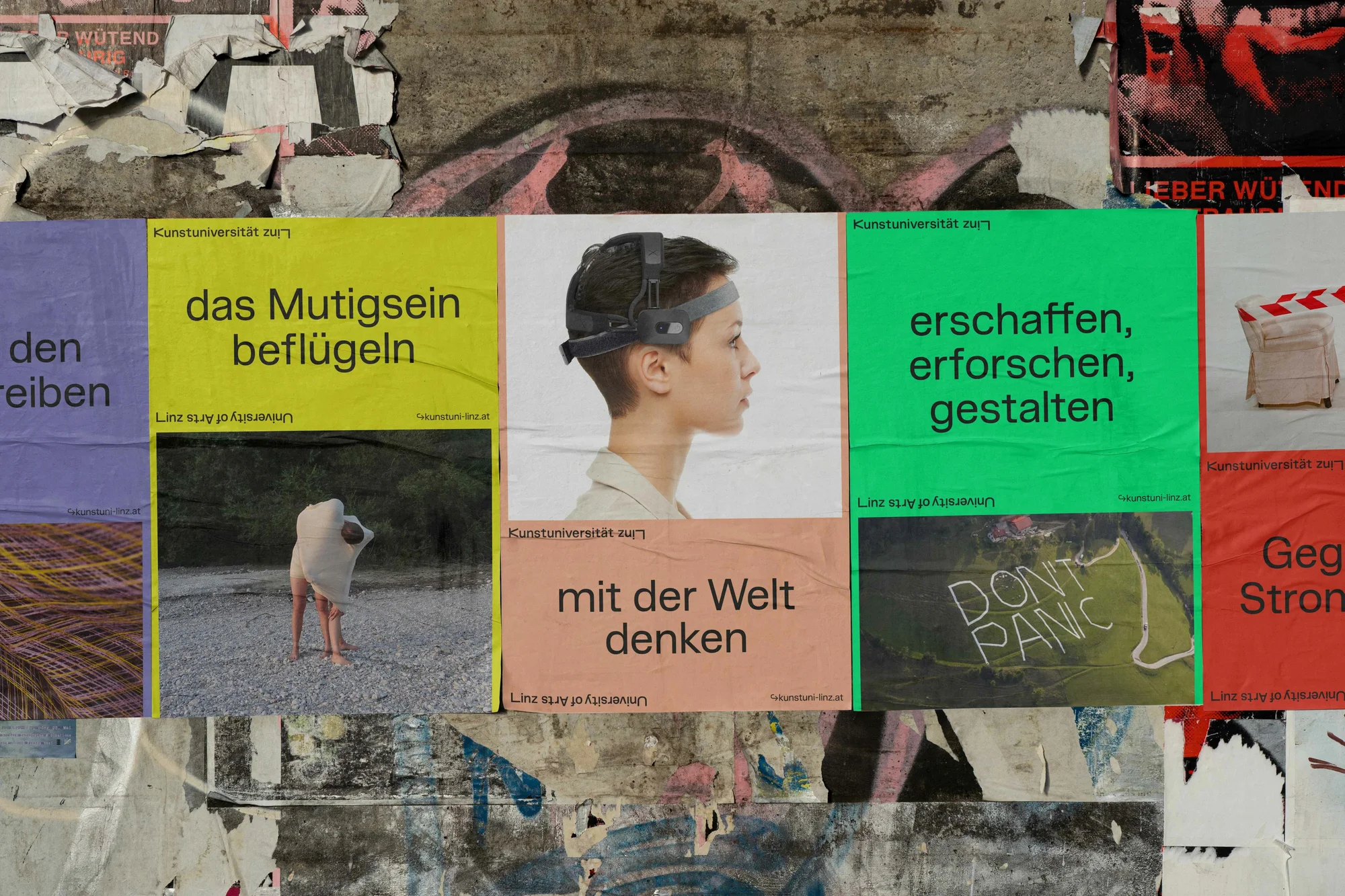 Close-up of posters on a wall displaying art images, text in German, and various university of arts graphics in an urban environment.