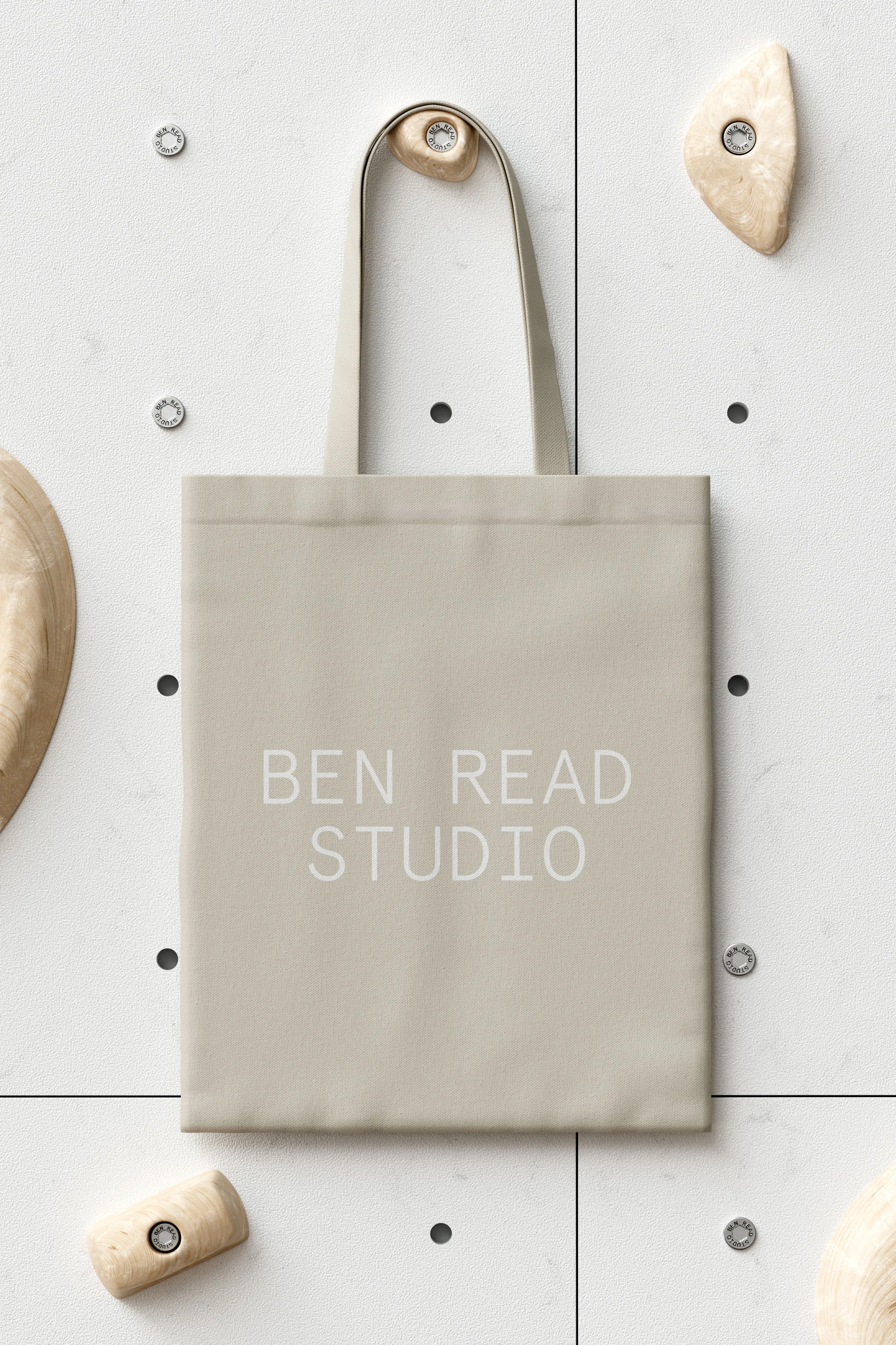 Beige tote bag hangs against a textured off-white wall with protruding climbing holds and the text 'BEN READ STUDIO' printed on it.