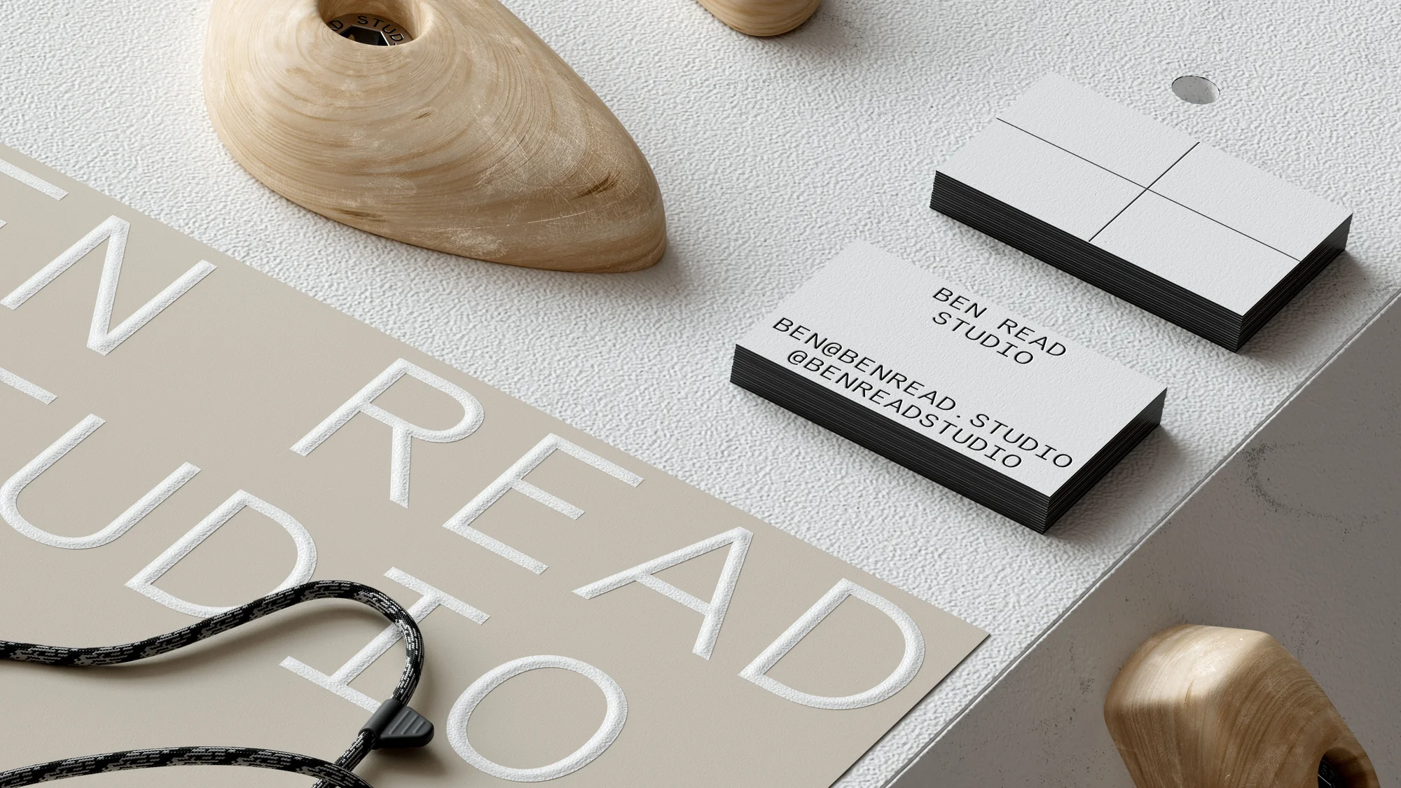 Close-up of business cards stacked near wooden shoe forms, featuring the text 'BEN READ STUDIO' on a textured off-white surface.