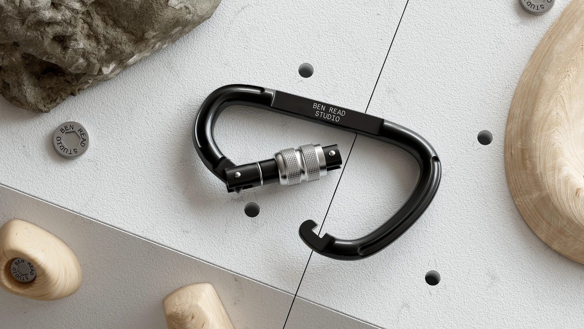 Close-up product shot of a black carabiner with silver hardware and the inscription 'BEN READ STUDIO' on a patterned grey background.