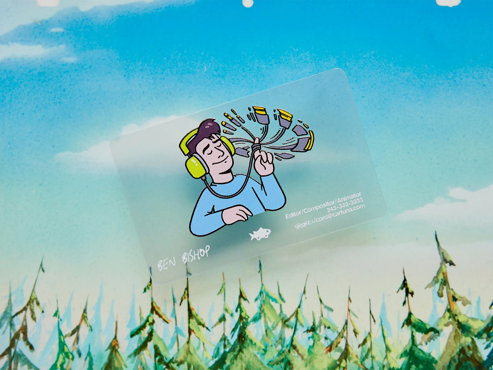 Illustration of a man wearing headphones with audio equipment attached to his head on a business card against a painted landscape.