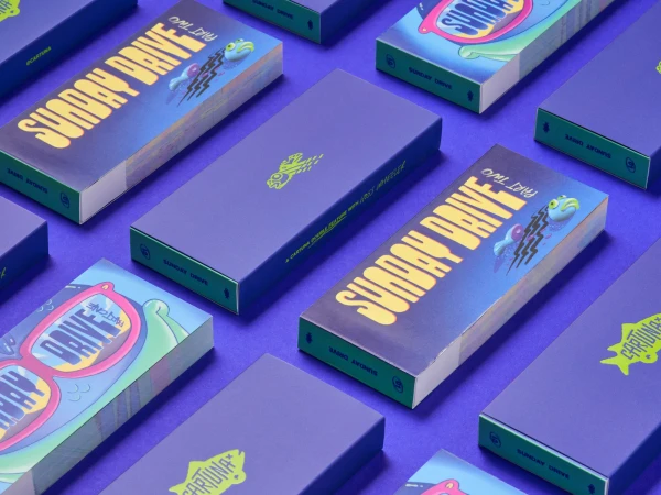 Overhead shot showcases multiple purple boxes with colorful graphics and titles, arranged in a repeating pattern on a purple surface.