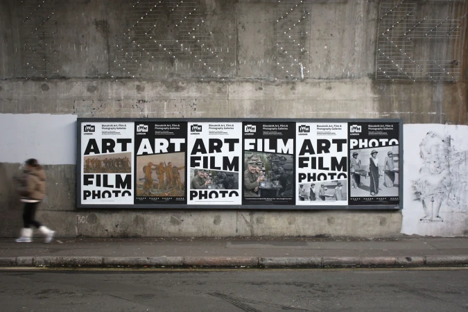 Public art installation featuring a series of black and white posters with text reading 'Art Film Photo' displayed on a concrete wall.